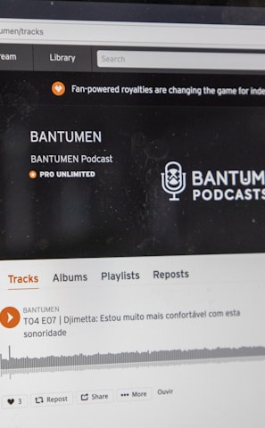 A computer screen displaying a website of an audio streaming service. The website showcases a podcast called BANTUMEN with the description 'Pro Unlimited.' There is a navigation bar with options including Home, Stream, Library, and more. A music wave graphic is visible below, along with a play button, social media interaction options such as re-post, share, and add to playlists. A banner at the top talks about fan-powered royalties, and there is a COVID-19 information widget to the side.